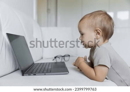 A little boy works on a laptop, presses buttons in a room at home. A small programmer, the concept of early development and online education. High quality photo