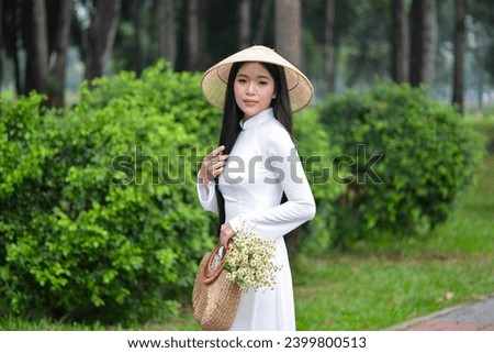 Royalty high quality free stock photo young beautiful girl wearing a white traditional costume of Vietnam with conical hat and holding a basket full of daisies