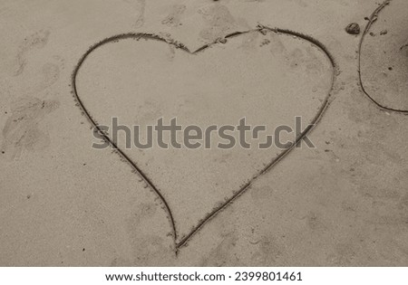Exterior photo view of a drawed traced or digged big large heart shape on teh sand to show love to people parents or special lover on the beach during summer