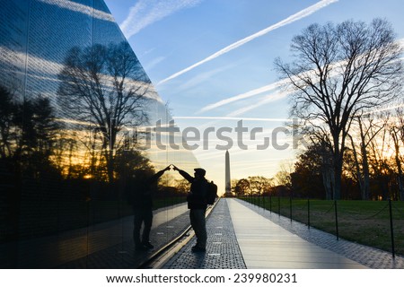 Washington DC - A Veteran looks for a name at Vietnam Veterans Memorial Wall  at sunrise Royalty-Free Stock Photo #239980231