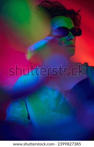 Bokeh effect. Portrait of handsome young man in stylish sunglasses posing over red background in neon light. Concept of youth culture, fashion and male beauty, emotions, inspiration, trends