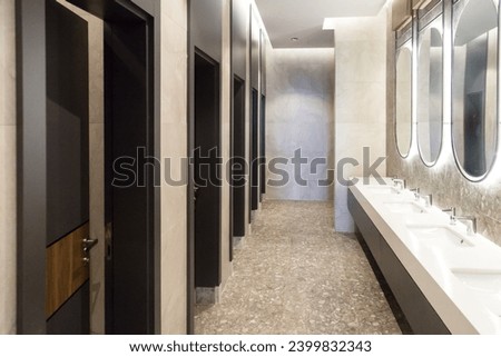 Stylish toilet with cubicles and illuminated oval mirrors.