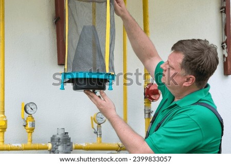 A man hangs reusable trap for flies and muskies near his house. Royalty-Free Stock Photo #2399833057