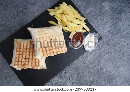 French tacos with fries, ketchup and mayonnaise , black stone plate , top view
