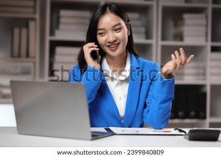 Businesswoman working overtime in the home office is using mobile phone to send messages and chat with colleagues, and analyzing monthly work schedule. Royalty-Free Stock Photo #2399840809