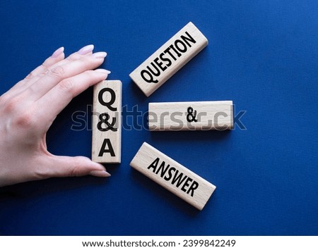 Q and A - Question and Answer. Wooden cubes with words Q and A. Businessman hand. Beautiful deep blue background. Business and Q and A concept. Copy space.