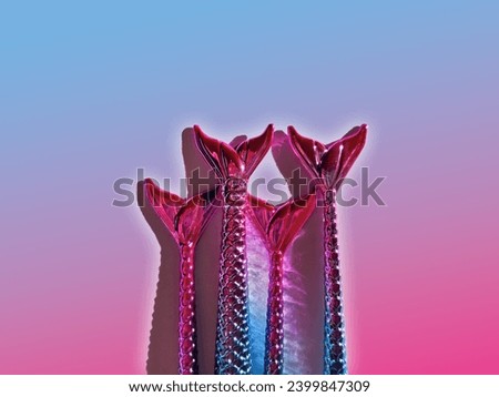 Close-up of the tips of glossy make-up brushes with a mermaid tail theme on a pink and blue background