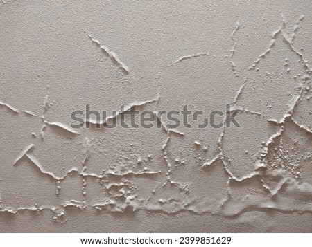 Abstract Rough Dry paint is peeling off the building wall.Close-up. Badly fixed building facade wall covered with cracks in stucco and paint. Missing patch of paint in the middle; crack with flappy. Royalty-Free Stock Photo #2399851629