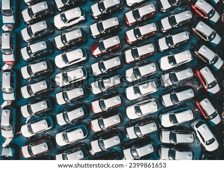 Aerial top down view of new cars parked in car parking lot. Car dealer parking lot full of new automobiles. New cars lined up for import and export business. Royalty-Free Stock Photo #2399861653
