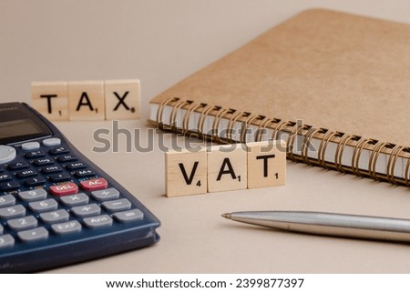 VAT written on a wooden cube on keyboard with office tools Royalty-Free Stock Photo #2399877397