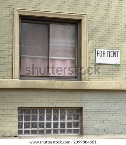 A For Rent sign on the side of an apartment building next to two windows in Pittsburgh, Pennsylvania, USA 