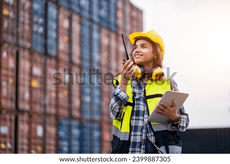 Female workers in the container industry transporting imports and exports of goods to the shipping business. Confident engineer in container terminal. Royalty-Free Stock Photo #2399887305