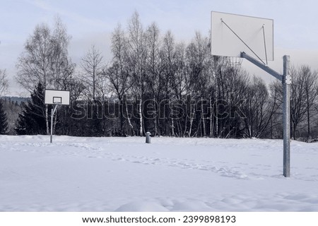 Basketball court covered with snow on a winter day with no people