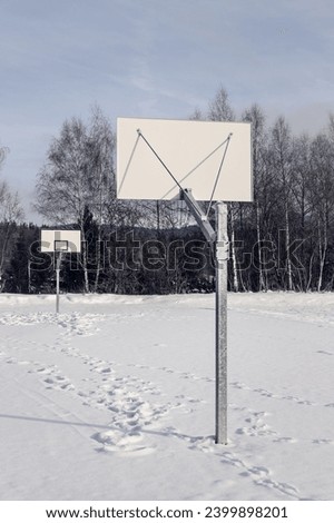 Basketball court covered with snow on a winter day with no people