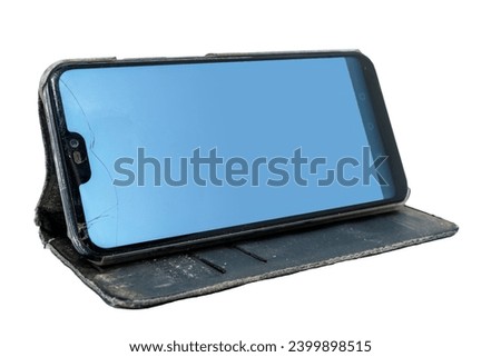 Used smart phone with cracked screen in a flip case, placed in horizontal position. Isolated on white background with clipping path