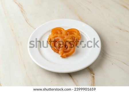 Jalebi served in a white plate against white marble background Royalty-Free Stock Photo #2399901659