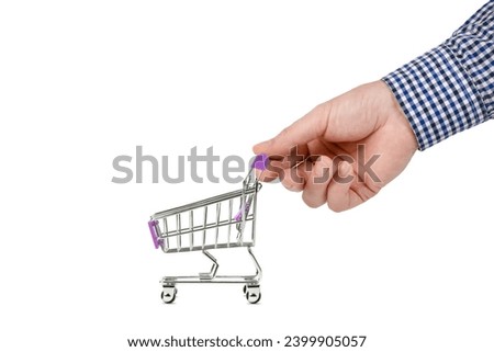 A man's hand holds an empty toy shopping cart in a supermarket. Conceptual image. Isolated on a white background.
