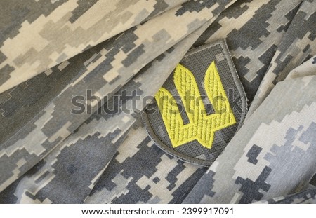 Symbol of Ukrainian army on the camouflage uniform of a Ukrainian soldier. The concept of war in Ukraine, patriotism and protecting your country from russian occupiers
