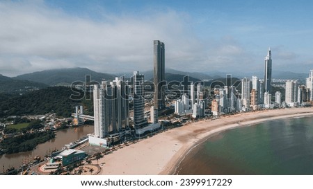 Aerial photo of the beachfront of Balneário Camboriú, on the coast of Santa Catarina, southern Brazil, with very tall buildings, a wide strip of sand, blue sea, speedboats, luxurious city, tourist