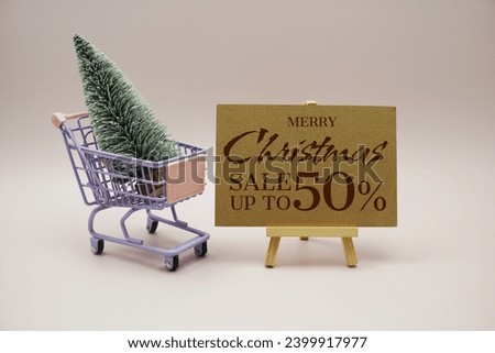 Christmas sale 50% off text message with Miniature Model Winter Pine tree on trolley shopping cart on pink background