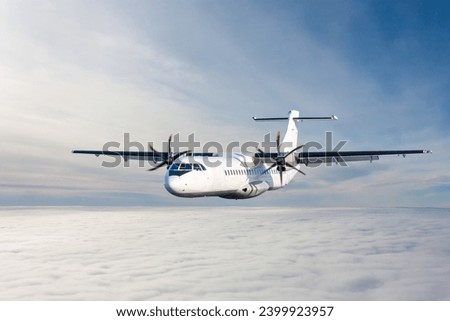 White passenger turboprop aircraft flies in the air above the clouds Royalty-Free Stock Photo #2399923957