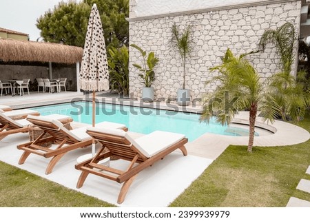 Tropical and Mediterranean style poolside concept in boutique hotel garden. Poolside lifestyle idea. Royalty-Free Stock Photo #2399939979