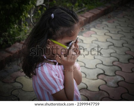 Kid girl Wearing black sunglasses in park.Standing bravely on footpath with pink cloth.Ai photo filter editing of dark shades.
