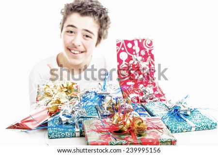 Christmas gifts in packages with colorful ribbons. In the background blurred boy smiles and makes success sign