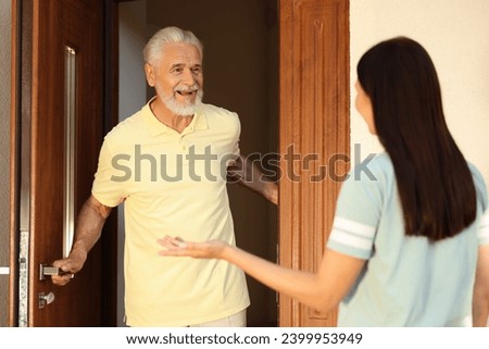 Friendly relationship with neighbours. Young woman visiting senior man Royalty-Free Stock Photo #2399953949