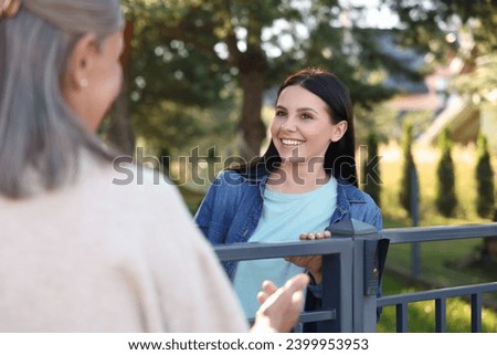 Friendly relationship with neighbours. Happy women near fence outdoors Royalty-Free Stock Photo #2399953953