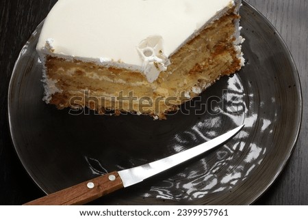 A piece of white cake with marzipan under dark lighting. Close-up	
