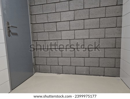 gray concrete blocks of the walls of a purpose-built warehouse with a door to a garage of austere design Royalty-Free Stock Photo #2399975177