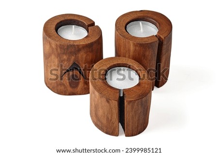 Three wooden candlesticks from a cut tree with a crack with candles isolated on a white background.