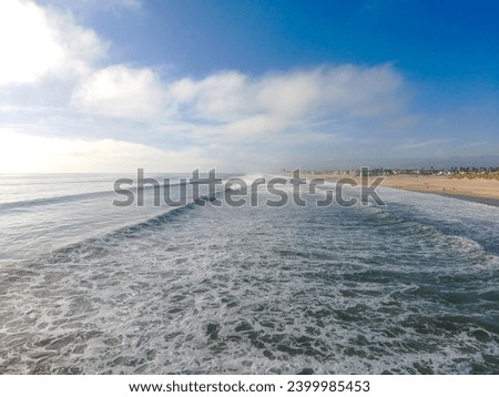 a breathtaking shot of the deep blue ocean water and the waves breaking as they roll in to the beach with blue sky and clouds at Oxnard State Beach Park in Oxnard California USA
