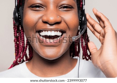 Close up shot portrair of delighted smiley cheerful African American woman with braids wearing wireless headset headphones supporting people online receiving call from customers.
