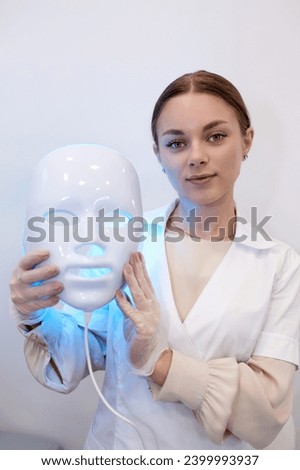 Beautiful young woman getting a led light therapy mask treatment for her face