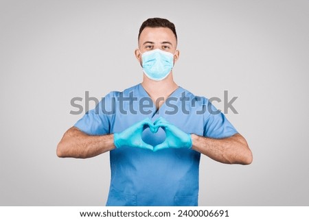 Caring male nurse in scrubs and mask makes a heart shape with gloved hands, symbolizing compassion and love in healthcare during challenging times