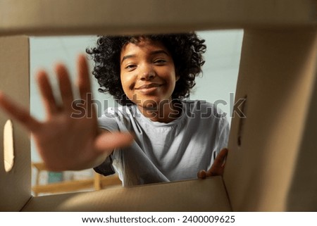 Inside of cardbox bottom view. African girl unpacking delivery looking in box. Woman opening carton box. Female getting parcel looking at delivered goods items. Satisfied client positive feedback Royalty-Free Stock Photo #2400009625