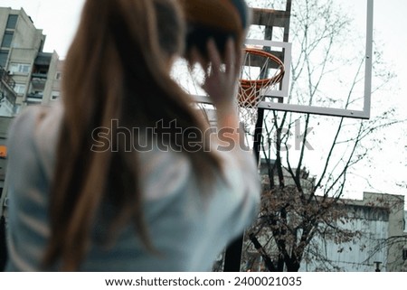 a girl plays basketball on the court in front of an apartment building in the city