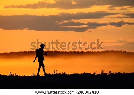 dusty sunset sun silhouette of a photographer walking away