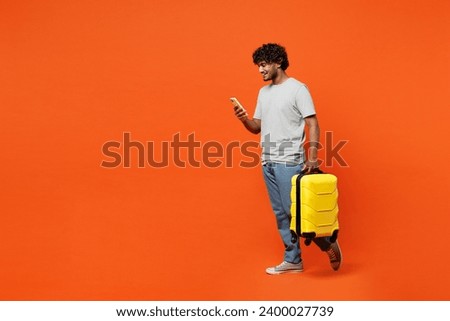 Full body traveler woman wear casual clothes hold suitcase mobile cell phone isolated on plain orange background. Tourist travel abroad in free spare time rest getaway. Air flight trip journey concept
