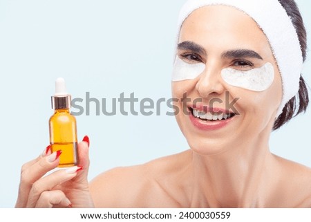 Senior woman smiling while holding a skincare product bottle in her hand Royalty-Free Stock Photo #2400030559