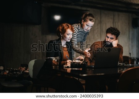 Business team working late, analyzing sales stats, planning project for market expansion. Coordinating tasks, sharing ideas, persistently working extra hours for business growth and success. Royalty-Free Stock Photo #2400035393