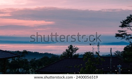 In the picture, the sky is expansive with alluring shades of pink, creating a dramatic scene. The soft, variegated clouds form interesting patterns in the sky, adding a touch of beauty to the twilight