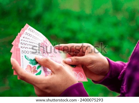 Hands of person counting banknotes, People counting Nicaraguan 500 cordobas banknotes Royalty-Free Stock Photo #2400075293
