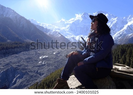 Asian female Tourist admiring the scenic view of the snow capped Nanga Parbat mountain and Rakhiot black glacier on Fairy Meadows on Karakoram Highway, Pakistan.