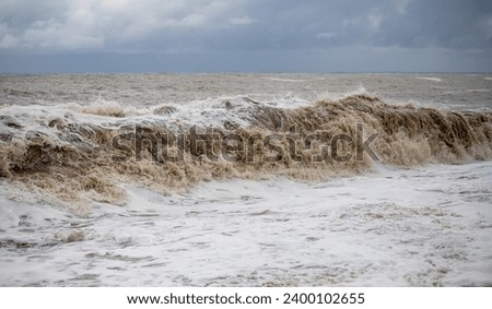 Large waves hit the shore. Storm at sea, storm warning on the coast. Thunderclouds and large sea waves during a storm.