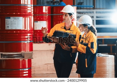 Two factory workers or inventory inspector conduct professional inspection on hazardous chemical barrels in warehouse, chemistry storage workplace and industrial profession concept. Exemplifying Royalty-Free Stock Photo #2400129905