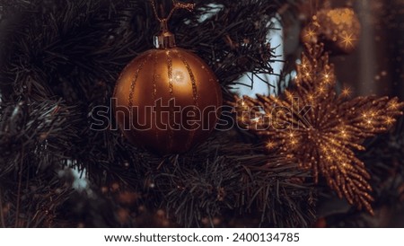 Christmas tree decorated with golden colored ball, gold tinsel star and apple on blurred background.  New Year and Christmas holidays concept.