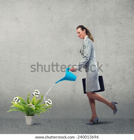 Businesswoman with can watering dollar money tree